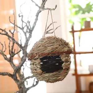 Detailed close-up view of a hand-woven straw bird nest hanging on a rustic tree branch.