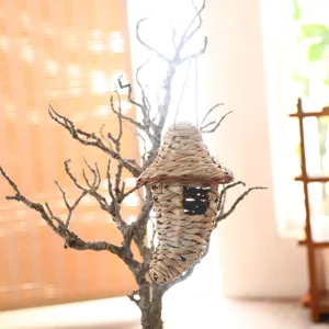 detail view of a handcrafted woven grass bird house hanging on a dry branch decor
