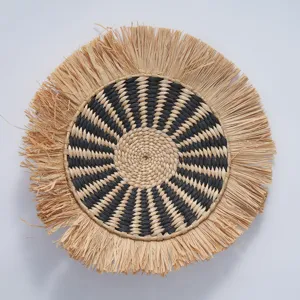 Handmade woven wall hanging detail showing black natural straw pattern and boho fringe texture.