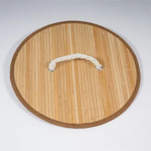 Close-up detail of round woven bamboo storage basket lid with fabric handle and brown trim.