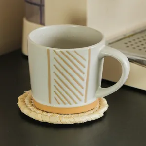 Handgemaakte keramische koffiekop met geometrische strepen en natuurlijk stro onderzetter
