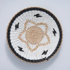 Close-up detail of a round woven wall hanging basket with black and white bohemian pattern.