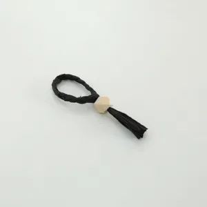 Detailed view of the black woven napkin ring showcasing the wooden bead and tassel detail.