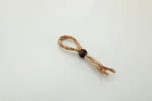 Handmade straw napkin ring detail shot, showing natural woven grass and wood bead craft.