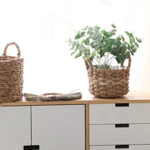 Detailed view of handmade woven straw basket planter with artificial eucalyptus greenery for home decor.