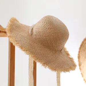 Detailed closeup view of the handmade straw sun hat featuring frayed edge and lace ribbon.