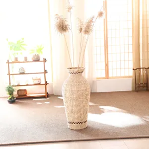 Detailed view of a natural woven floor vase filled with dried pampas grass in a bright room.