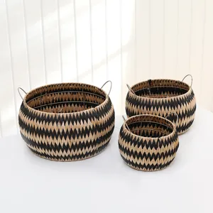 Detail shot of hand-woven straw storage baskets set with metal handles and geometric pattern.