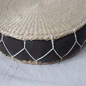Handmade natural straw woven round floor cushion detail, vintage tatami pouf for home decor.