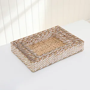 Close-up detail shot of nested natural straw woven storage baskets on a clean white surface.
