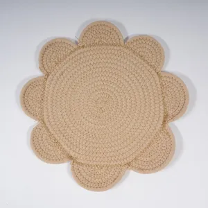 Close-up detail of a beige braided cotton flower placemat, showing fine texture and edges.