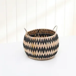 Woven straw storage basket with metal handles, black and white geometric pattern for home decor.