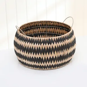 Hand-woven straw storage basket with black zig-zag pattern and metal handles for home organizer.