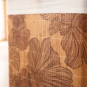 Detalle de cesta de ropa de bambú con motivo floral y diseño de textura natural.