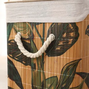 Vista detallada de cesta para ropa sucia de bambú con estampado tropical y asas.