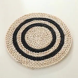Handmade corn husk braided placemat featuring black and white concentric circular pattern details.