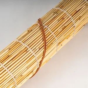 Detailed close-up of rolled natural reed curtain showing neat weaving and brown tie rope.