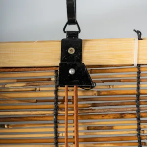 Detailed view of bamboo roller blind hanging mechanism with natural reed slats and metal hook.