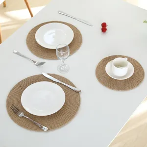 Close-up detail of natural jute woven placemat on white table with elegant tableware setup.