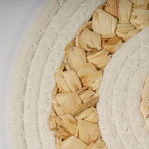 Close-up detail of braided corn husk placemat, natural straw and white cotton woven texture.