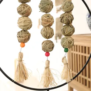 Close-up detail of hanging woven grass chew balls with colorful beads for pet birds.