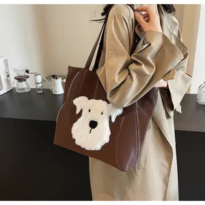 Detailansicht der braunen Ledertasche mit weißem flauschigen Hundepatch und Reißverschluss.