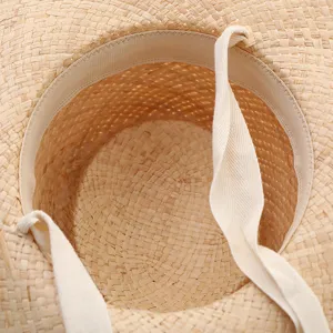 Close-up detail of straw sun hat inner weave and strap, natural texture raffia design.
