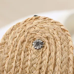 Handmade raffia straw sun visor hat detail with vintage floral metal button for summer beach.