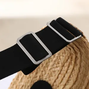 Close-up detail of the adjustable elastic strap and metal buckle on a woven summer straw hat.