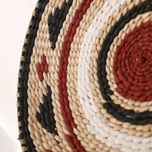 Handwoven straw wall hanging or placemat with colorful concentric circles for home decor.