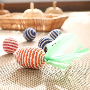 Close-up detail of hand-woven straw carrot toy with green raffia leaves, rustic eco-friendly texture.