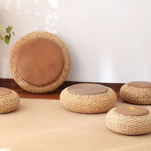 Round straw woven floor cushion with brown leather center, tatami meditation mat for home.