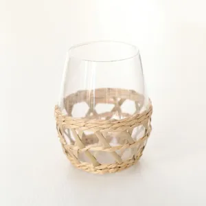 Vista detallada de vaso de vidrio transparente con soporte de paja, estilo vintage.