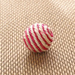 Closeup of a red and white woven ball detail, handmade straw craft for decoration.