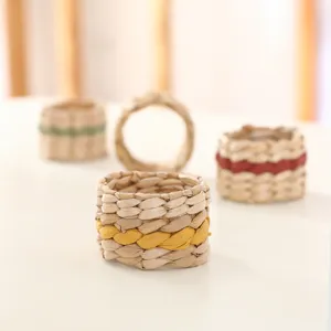 Hand-woven straw napkin rings with colorful decorative stripes for table setting detail.