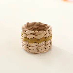 Handmade woven napkin ring with green stripe, rustic table decor detail for dining setup.