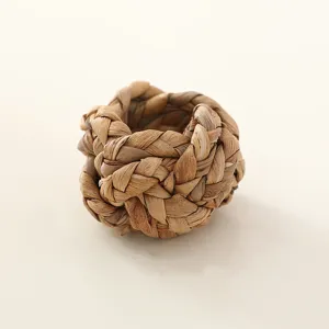 Close-up detail of hand-woven straw napkin ring, rustic natural plant fiber table decor texture.