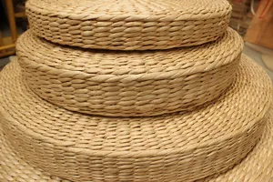 Detailed shot of thick straw woven meditation pouf, natural plant fiber tatami cushion texture.