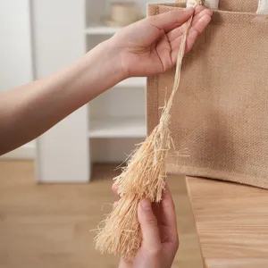 Handgemachte Bast geflochtene Quasten Anhänger Detail, ideales Accessoire für lässige Jutebeutel.