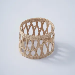 Dettaglio coprivaso in paglia intrecciata, texture in fibra naturale, design traforato.