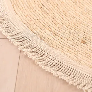 Handmade round woven rug detail close up showing natural straw texture and elegant fringe edge.