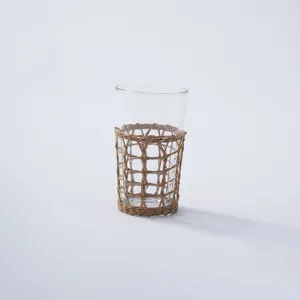 Handmade rattan woven glass cup sleeve detail, natural straw braided holder for drinking glass.