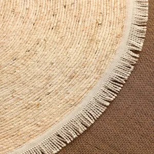 Handmade round woven jute straw rug detail with white fringe for bedroom home decoration.