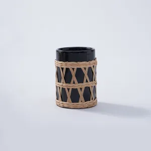 Detailed view of black glass bottle featuring handmade natural rattan woven protective sleeve cover.