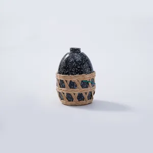 Close-up detail of the black speckled bottle with handmade woven straw protective net cover.