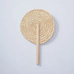 Handmade woven straw fan detail shot showcasing natural plant material and solid wood handle craftsmanship.