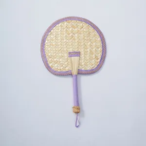 Hand-woven straw fan detail showing the intricate weaving texture and purple fabric trim.