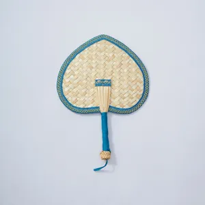 Closeup of handcrafted straw fan with blue edge, traditional woven texture detail for summer.