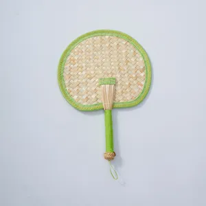 Hand-woven natural straw fan with green fabric border for summer cooling and home decor.