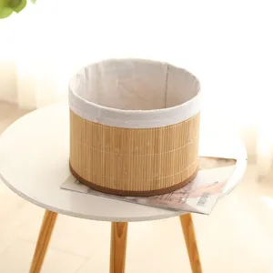 Close-up detail of a round woven bamboo storage basket with fabric lining on a white table.